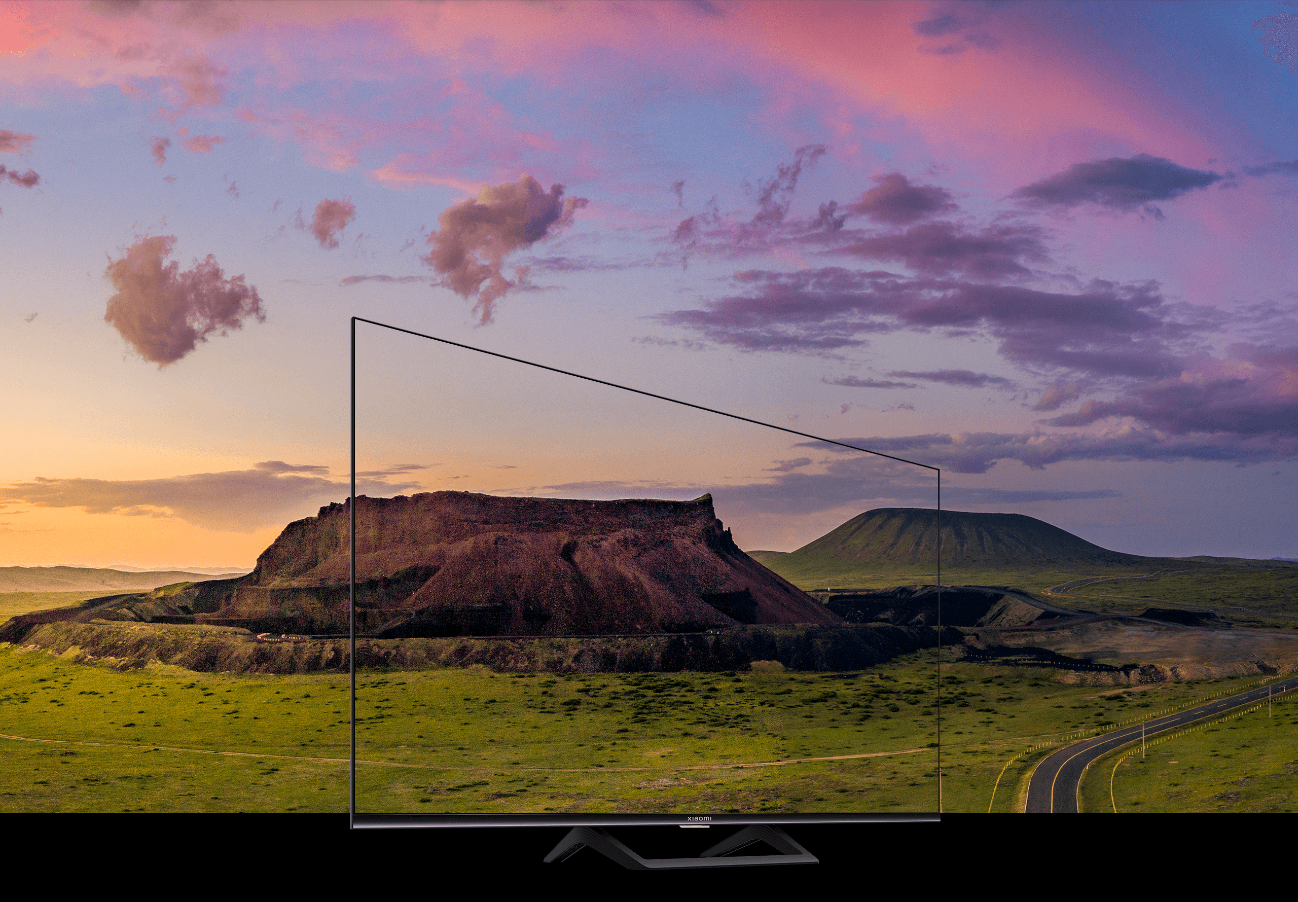 Xiaomi Mi TV A2 55 вид спереди на подставке, экран с природным пейзажем на закате