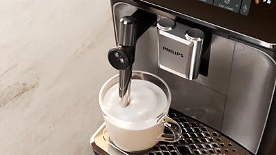 Philips EP3321/40 приготовление капучино — диспенсер кофемашины над чашкой с молочной пеной